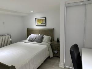 a white bedroom with a bed and a chair at Vihome005C1-Beautiful House near Eglinton subway station in Toronto