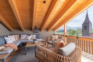 a porch with couches and chairs and a wooden ceiling at Chiemgauloft , 5 Sterne Ferienwohnung am Chiemsee in Übersee