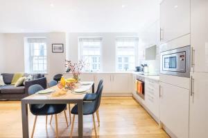 City of London - CityApartmentStay في لندن: مطبخ وغرفة معيشة مع طاولة وكراسي