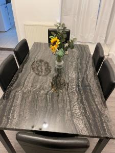 une table argentée avec un vase de fleurs sur elle dans l'établissement SAV 3 Bedroom House Chiltern Rise Luton, à Luton