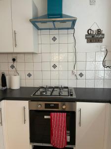 - une cuisine avec une cuisinière et une serviette rouge et blanche dans l'établissement SAV 3 Bedroom House Chiltern Rise Luton, à Luton