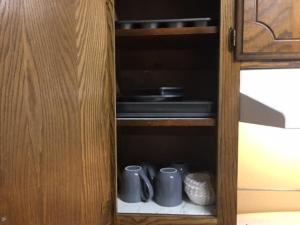 un armario de madera con tres tazas. en Close to Fort Sill Upstairs 1 bedroom apartment en Lawton