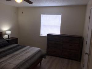 ein Schlafzimmer mit einem Bett, einer Kommode und einem Fenster in der Unterkunft Cozy Upstairs 1 Bedroom Apartment close to Fort Sill in Lawton