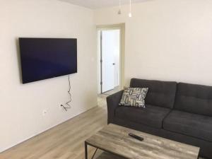 ein Wohnzimmer mit einem Sofa und einem TV an der Wand in der Unterkunft Cozy Upstairs 1 Bedroom Apartment close to Fort Sill in Lawton