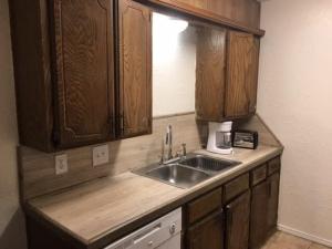 eine Küche mit einer Spüle und Holzschränken in der Unterkunft Cozy Upstairs 1 Bedroom Apartment close to Fort Sill in Lawton