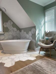 a bathroom with a large tub and a chair at Brand New! Bagpipers Luxury Hideaway at Ard Craig House Glencoe in Glencoe