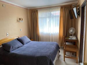 a bedroom with a blue bed and a window at Hotel Libertador Bernardo O´Higgins in Chillán