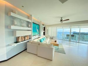 una sala de estar con muebles blancos y vistas al océano. en Departamento frente al mar, en Cancún