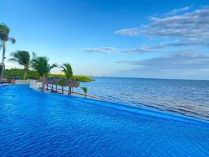 una piscina junto al océano con palmeras en Departamento frente al mar, en Cancún