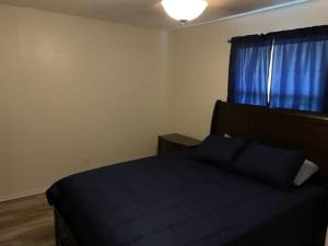 um quarto com uma cama com lençóis azuis e uma janela em Comfortable downstairs 2 bed next to Fort Sill em Lawton