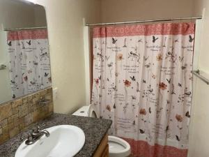 uma casa de banho com um lavatório, um WC e uma cortina de chuveiro. em Comfortable downstairs 2 bed next to Fort Sill em Lawton