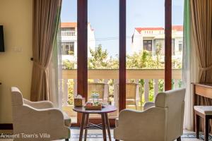 Habitación con sillas, mesa y ventana grande. en Dubai-Loius Residence en Hoi An