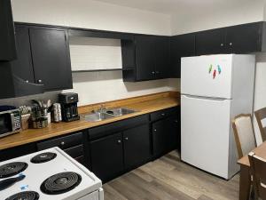 a kitchen with black cabinets and a white refrigerator at Cozy 3-Bedroom, 1-Bath Home Close to Fort Sill in Lawton