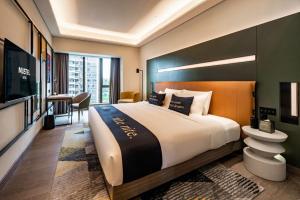 Habitación de hotel con cama grande y TV en MUSTEL Hotel Guangzhou Nansha, en Guangzhou
