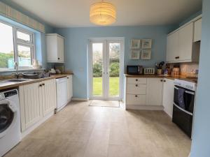a kitchen with white cabinets and a washer and dryer at Bryn Eithin in Benllech