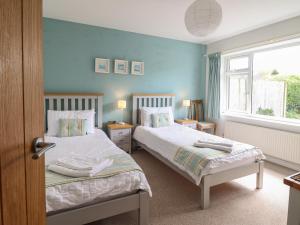 two beds in a bedroom with blue walls and a window at Bryn Eithin in Benllech