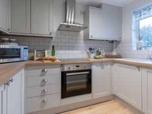 a kitchen with white cabinets and a stove top oven at Wren Cottage in Stratford-upon-Avon