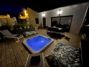 Un grand bain à remous est installé sur une terrasse en bois. dans l'établissement Maison T4 Climatisée avec Jacuzzi à Lagord, à Lagord