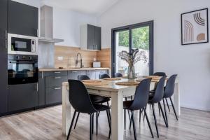 une cuisine avec une table en bois entourée de chaises. dans l'établissement Maison T4 Climatisée avec Jacuzzi à Lagord, à Lagord