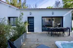 une terrasse avec une table, des chaises et une piscine dans l'établissement Maison T4 Climatisée avec Jacuzzi à Lagord, à Lagord