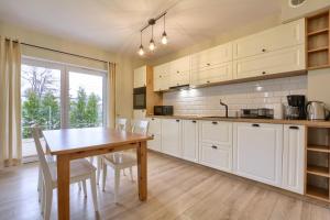 a kitchen with a wooden table and white cabinets at Apartament NavyBlue in Szklarska Poręba