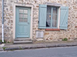 un edificio con una puerta azul y una ventana en La maison de Clémentine, en Héricy