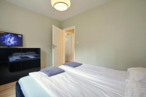 シュクラルスカ・ポレンバにあるApartament NavyBlueのベッドルーム(白い大型ベッド1台、薄型テレビ付)