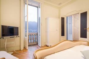 a bedroom with a bed and a tv and a window at Villa Joy On The Lake in Moltrasio