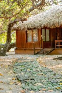 a small hut with a grass roof and a pathway at Refugios Parajuru - Pavilhão in Parajuru