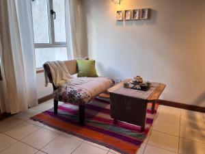 uma sala de estar com uma cadeira e uma mesa em Narcisos y Amapolas en Ushuaia em Ushuaia