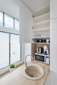 a kitchen with a sink and a microwave on a counter at Serene Nemunas River View apartment near McDonald by Polo Apartments in Kaunas