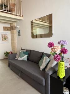 un sofá gris en una sala de estar con flores en un jarrón en Messapia, la casa fra i due mari, en Cellino San Marco