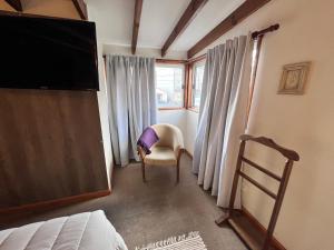 um quarto com uma cama, uma cadeira e uma janela em Narcisos y Amapolas en Ushuaia em Ushuaia