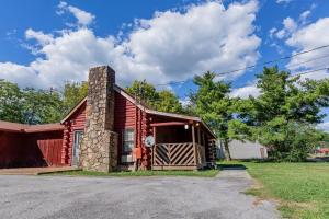 a red cabin with a stone chimney and a garage at Genuine log cabin minutes away from Chattanooga's top attractions in Chattanooga