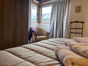uma cama num quarto com uma janela e uma cadeira em Narcisos y Amapolas en Ushuaia em Ushuaia