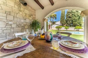 een houten tafel met borden en wijnglazen erop bij Villa Stella Maris Luxury 4BR Pool Beach in Roda de Bará