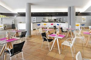 a restaurant with tables and chairs and a kitchen at Elba Castillo San Jorge & Antigua Suite Hotel in Caleta De Fuste