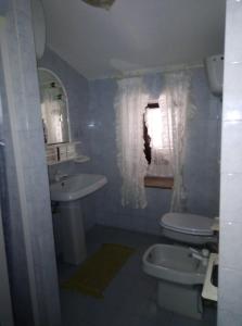 a bathroom with a sink and a toilet and a window at Casa Portopaglia in Gonnesa +8 photos