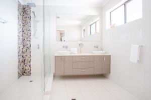 a white bathroom with two sinks and a shower at Pet Friendly family Home with Pool - Walk to Warana beach in Buddina