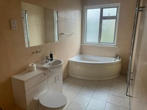 ein Badezimmer mit einer Badewanne, einem WC und einem Waschbecken in der Unterkunft HANDOVER 4 in London