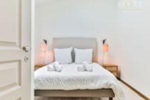 Schlafzimmer mit einem Bett mit weißer Bettwäsche und Kissen in der Unterkunft Maison au pied de la plage in Les Sables-dʼOlonne