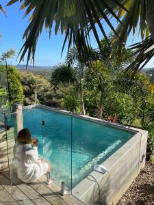 a woman sitting next to a swimming pool at The Opal at Coolum - Mountain and Ocean Views in Yaroomba