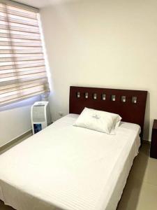 - une chambre avec un lit blanc et une fenêtre dans l'établissement Apartamento Zainos Villavicencio, à Villavicencio