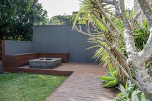 un jardin avec une terrasse en bois et un arbre dans l'établissement Moffat Beach, Large families & friends unite here!, à Caloundra