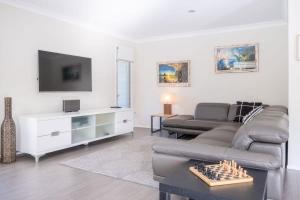 a living room with a couch and a tv at Moffat Beach, Large families & friends unite here! in Caloundra