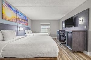 a hotel room with two beds and a flat screen tv at Clarion Pointe Tampa-Brandon Near Fairgrounds and Casino in Tampa