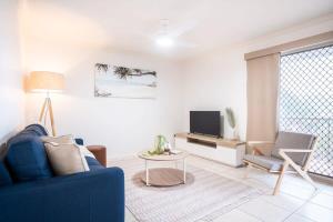 a living room with a blue couch and a tv at Spacious Apartment, Walk To Kings Beach in Caloundra