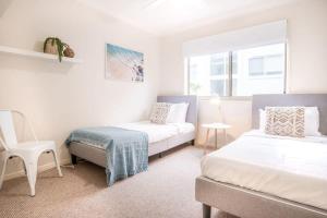 a bedroom with two beds and a chair in it at Spacious Apartment, Walk To Kings Beach in Caloundra