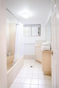 a white bathroom with a tub and a shower at Spacious Apartment, Walk To Kings Beach in Caloundra