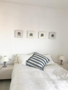 Una cama blanca con una almohada azul y blanca. en Narciso views, en Vilassar de Mar